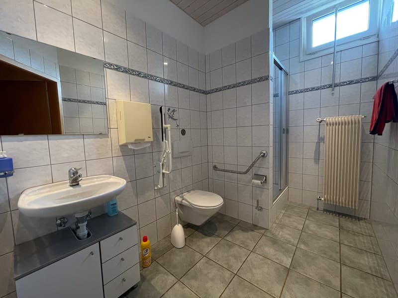 Tiled bathroom with a sink, toilet, and shower area. The bathroom has a private washing machine and appears to be well-equipped.