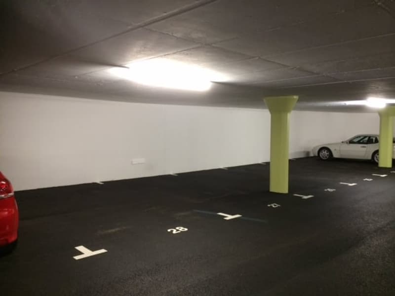 Underground parking lot with numbered parking spots and yellow support columns.