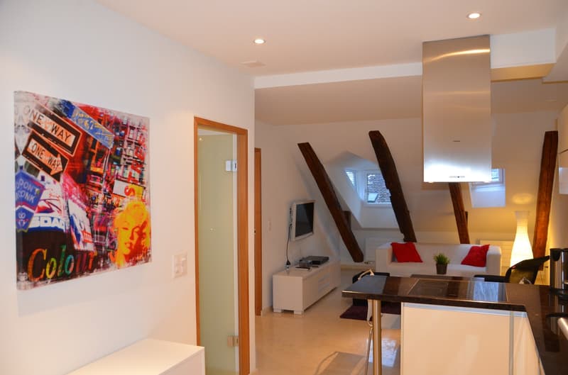 modern living room with white furniture, wooden beams, wooden floors, couch with red pillows, flat screen tv, artwork on the wall