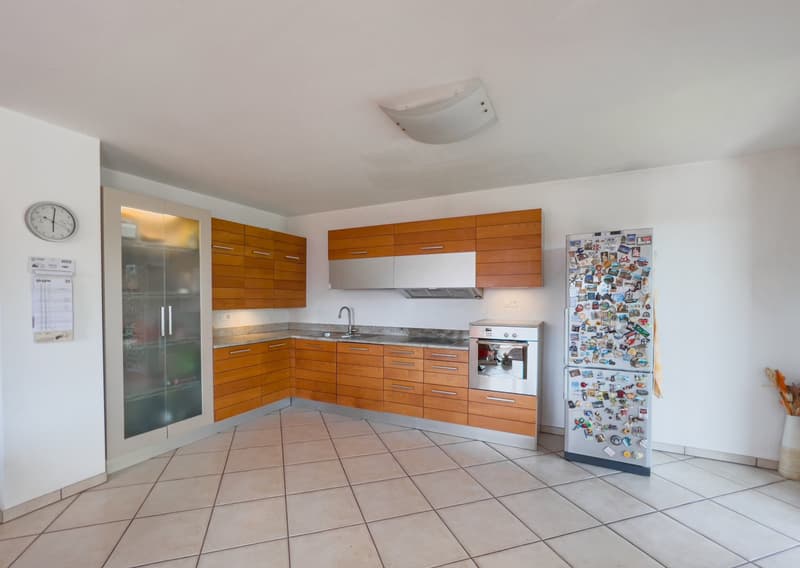 Open kitchen with granite countertops, wooden cabinets, modern appliances including a dishwasher and washing machine, white tiled floor, neutral color palette, ample natural light from windows