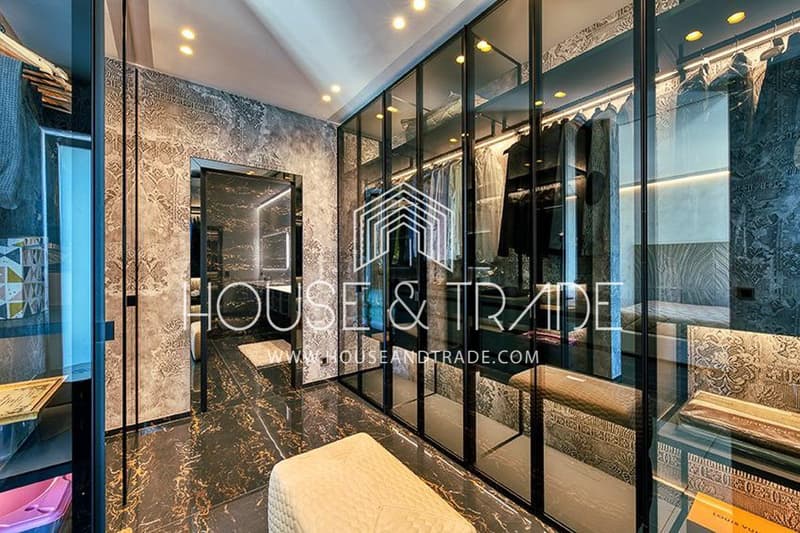walk-in wardrobe with hanging lights, large mirror, marble flooring, full-length glass wall