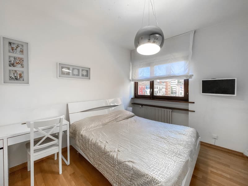 Bedroom with bed, desk, chair, radiator, window, pictures, lamp, TV