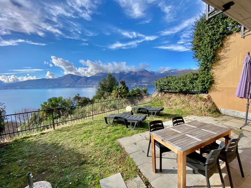 fenced garden with lawn, table and chairs, lounge chairs, closed umbrella, view of mountains and sea