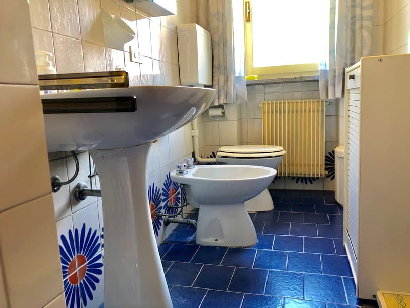 Bathroom with blue and white tile flooring, a pedestal sink, a toilet, and a radiator on the wall.