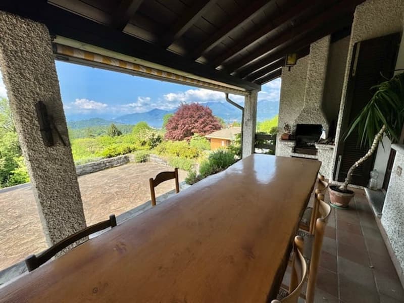 long wooden table, wooden chairs, covered balcony, grill, potted plant, outdoor garden, beautiful view