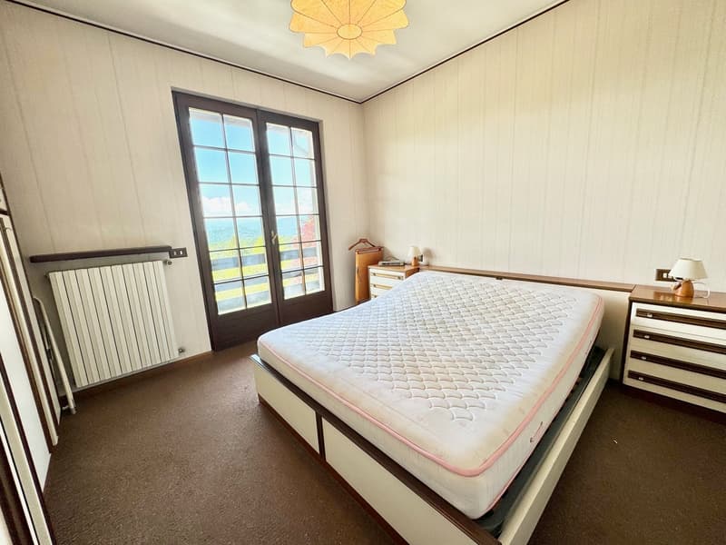 large bed, large window with view, lamp, wooden floor, wooden nightstands, white radiator