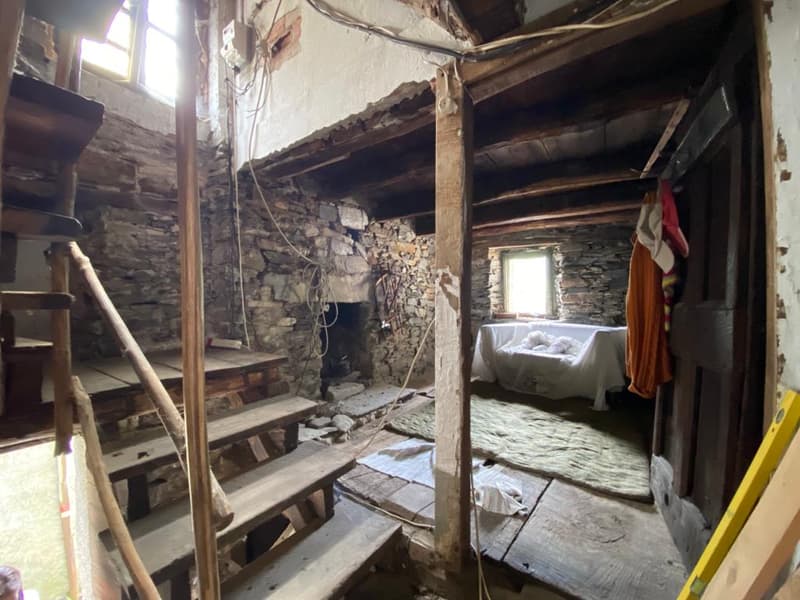 steep wooden stairs, fireplace in corner, stone walls, old and worn interior