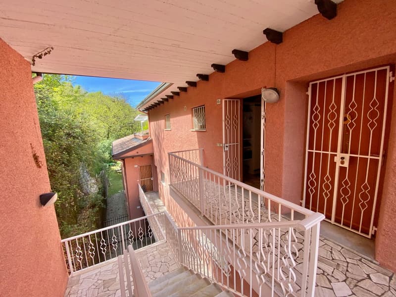 Two-story apartment building with orange stucco exterior, covered balconies, decorative metal railings, and stairs leading up to the entrances.