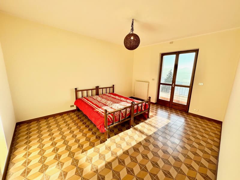 a bed with a red blanket, wooden railings, tiled floor, large window