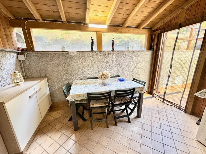a patio with tile flooring and a glass wall, a table with 6 chairs, and a white shelf above the table
