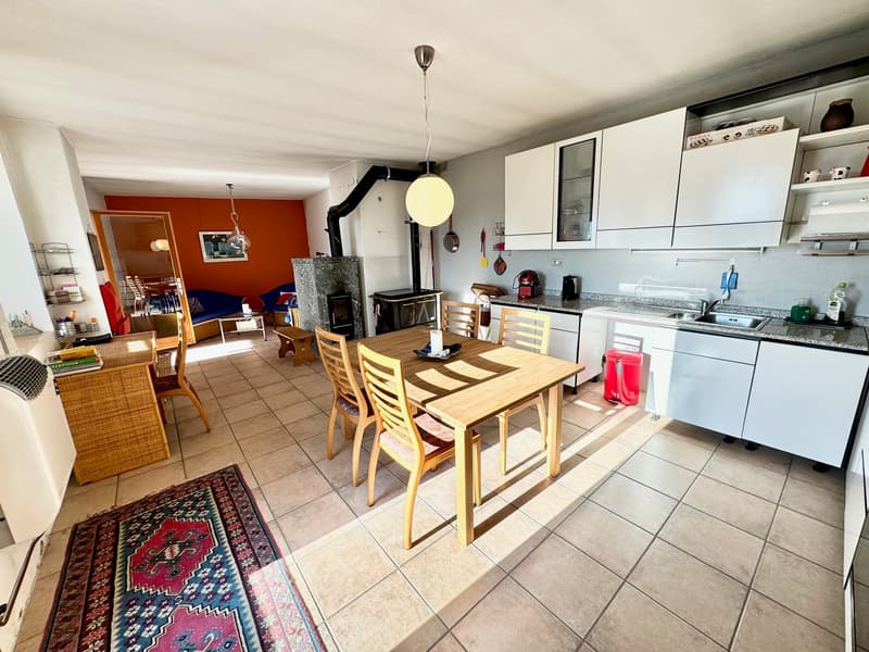 dining area with a wooden table and chairs, a fireplace, a tiled floor, white cabinets, a sink with a faucet, and a kitchen area with appliances