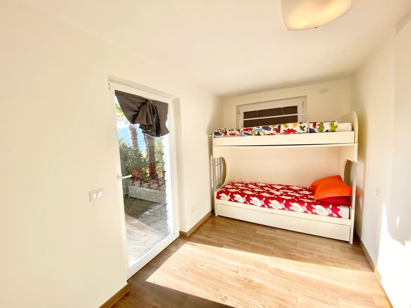 Bedroom with bunk bed, colorful bedding, and sliding glass door leading to a balcony or terrace