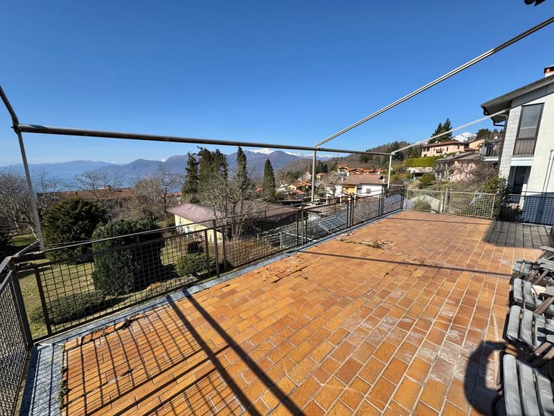 Large outdoor terrace with brick flooring, metal railings, and a panoramic view of the surrounding mountains and buildings