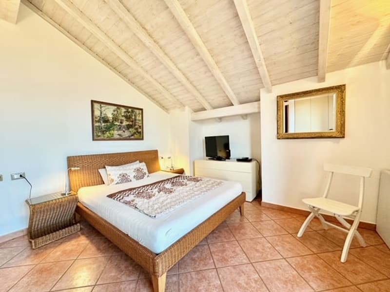 wooden bed, two nightstands, flat screen TV, mirror, framed picture, wooden chair, power outlet