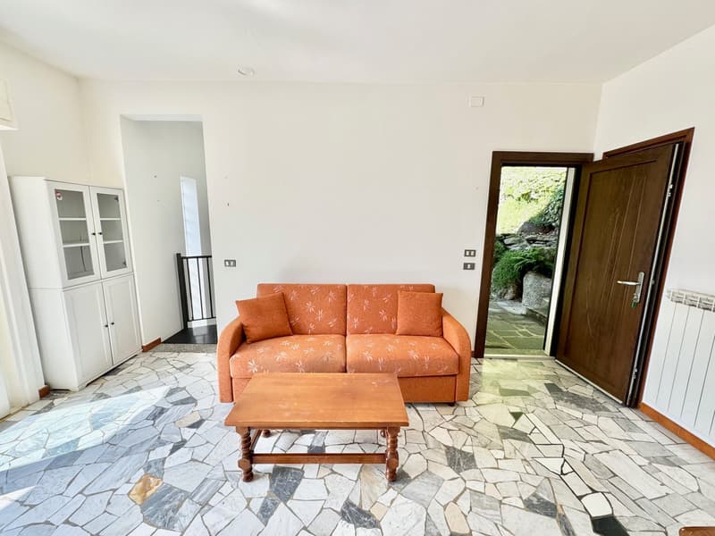 Living room with white walls, stone floor, orange sofa, wooden coffee table, white cabinet, wooden door
