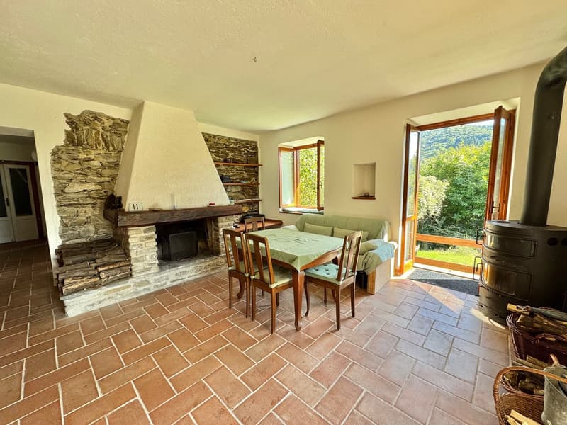 brick fireplace, wooden dining table and chairs, green sofa, large windows