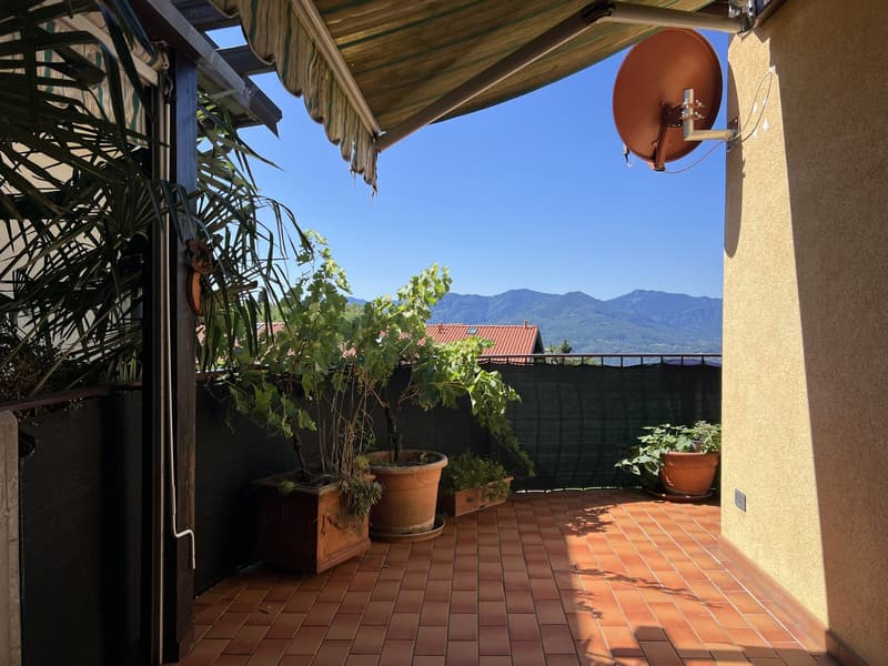 tiled floor, awning, satellite dish, potted plants, black railing, green fence, mountain view