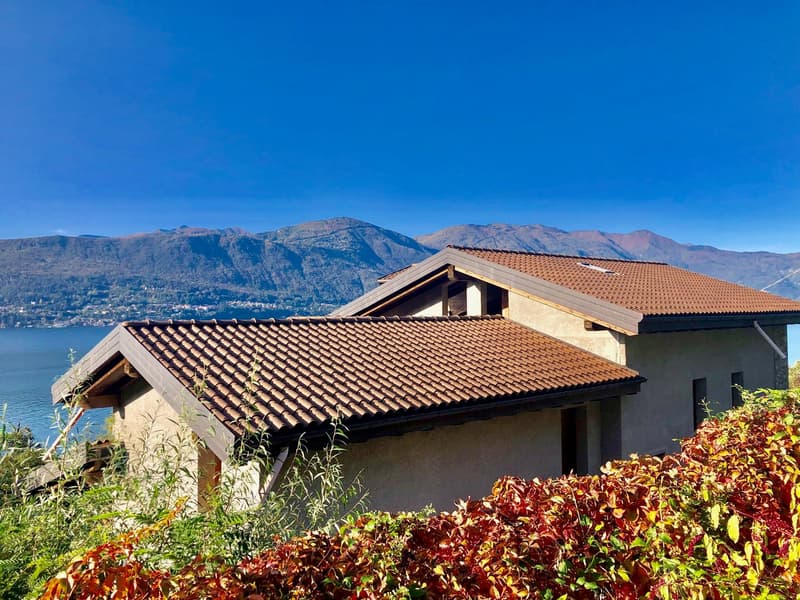 2 story house, brown roof, mountains in the background, water view