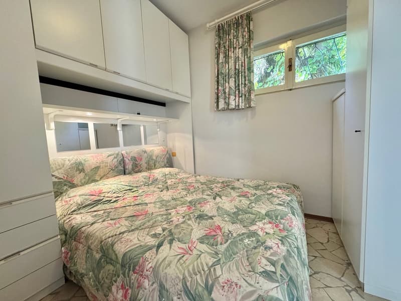 white cabinets, bed, floral bedspread, pillows, curtain, window