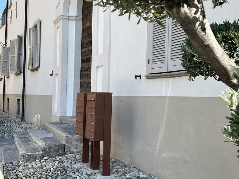 white stucco facade with brown mailboxes, window shutters, steps, pebbles