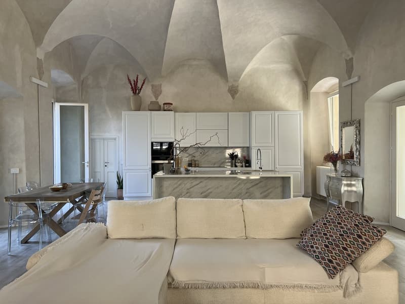 modern interior, white walls, ceiling with arched details, L-shaped sofa, dining table, marble kitchen island, white kitchen cabinets, open archways