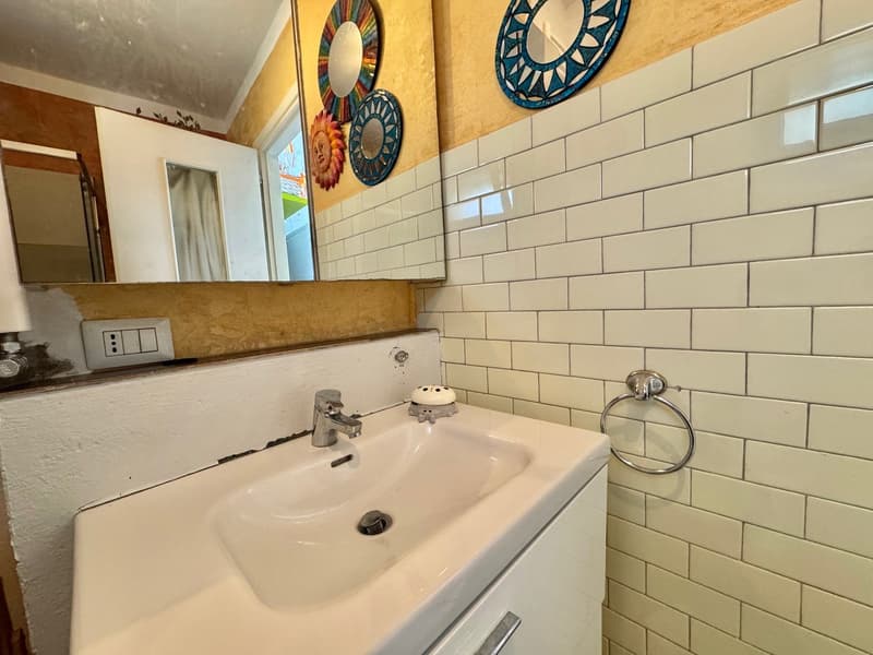 The image shows a bathroom with a white sink and faucet, a subway tile wall, and decorative circular mirrors on the wall.