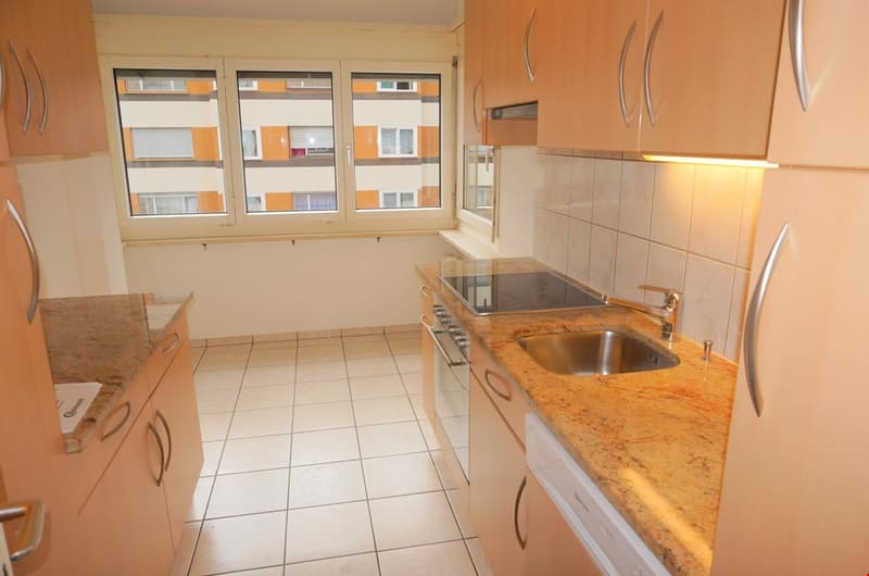 modern kitchen with granite countertops, stainless steel sink, gas stove, dishwasher, cabinets, and a window with a view of the building