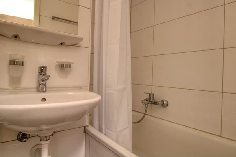 white tiles, white sink, mirror, bathtub, shower curtain