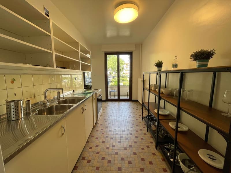 kitchen with sink, shelves, tiled floor, balcony with chair, plants, wine glasses
