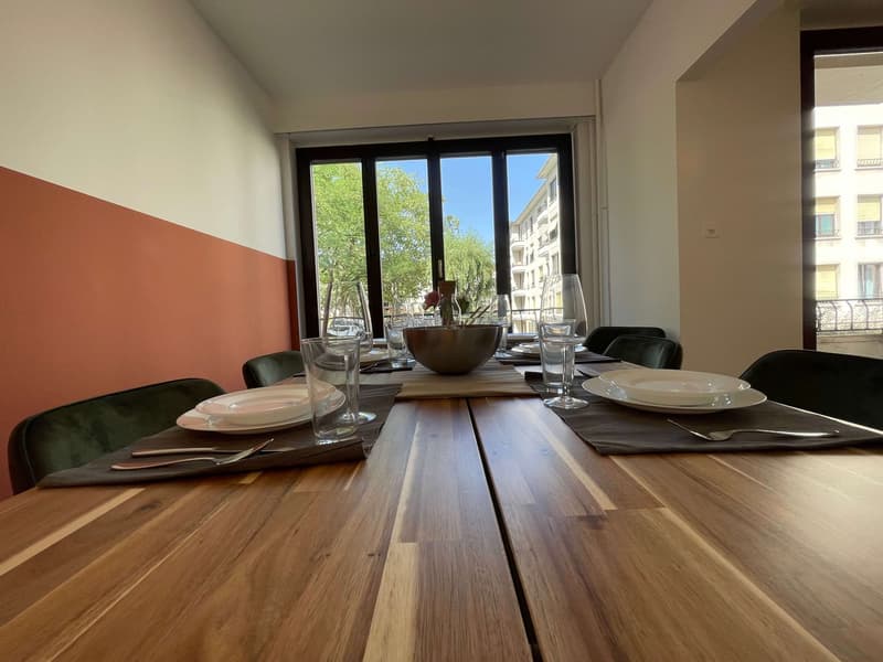 Dining room with a large wooden table, chairs, and a view of the outside