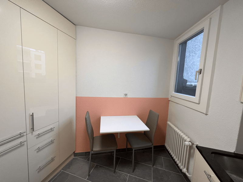 small room with a table, chairs, cabinets, and a window