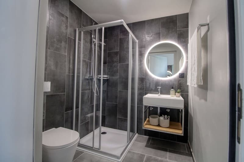 modern bathroom with shower, toilet, sink, mirror, and storage shelves