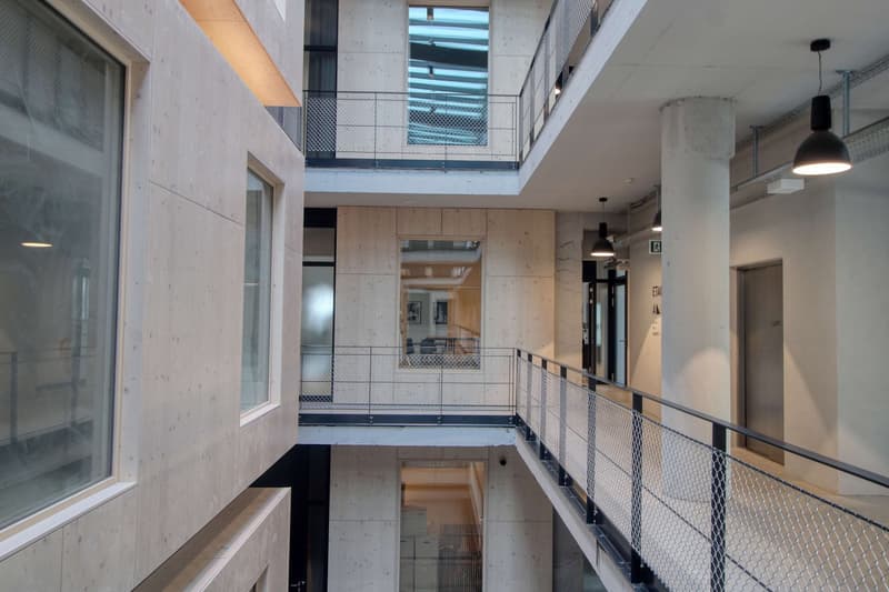 modern building, multiple floors, glass windows, metal railings, open spaces