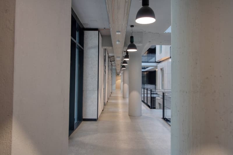 long corridor, white walls, white ceiling, hanging lamps, glass windows, metal railings