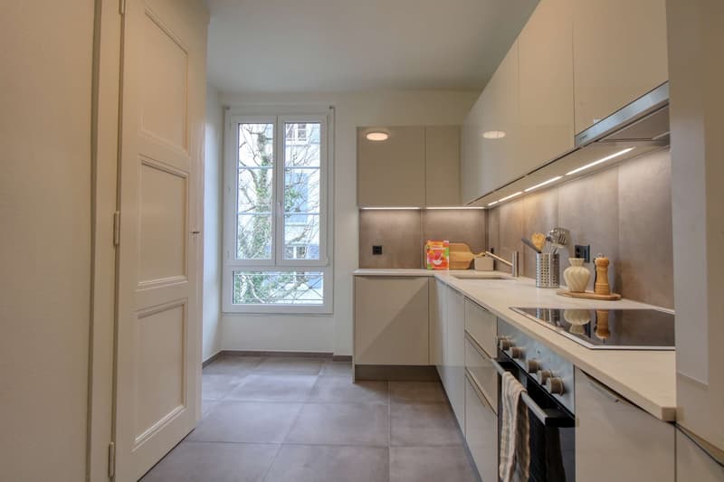 modern kitchen with white cabinets, tiled floor, large window with view, stainless steel appliances