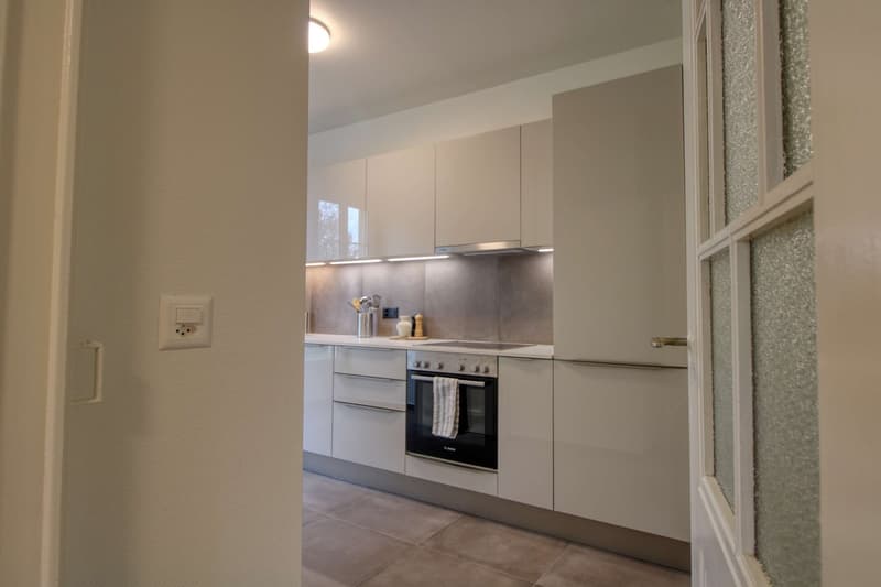 modern kitchen with white cabinets, tiled floor, built-in oven, dishwasher, countertop, power outlet