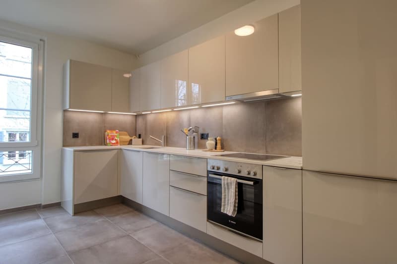 modern kitchen with white cabinets, tiled floor, Bosch oven, sink, refrigerator, countertop, window