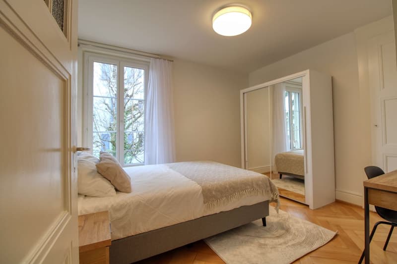 Bedroom with bed, nightstand, rug, mirror, and window with curtains