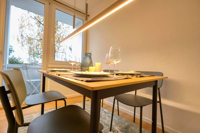 dining table with chairs, large windows, balcony, view of trees