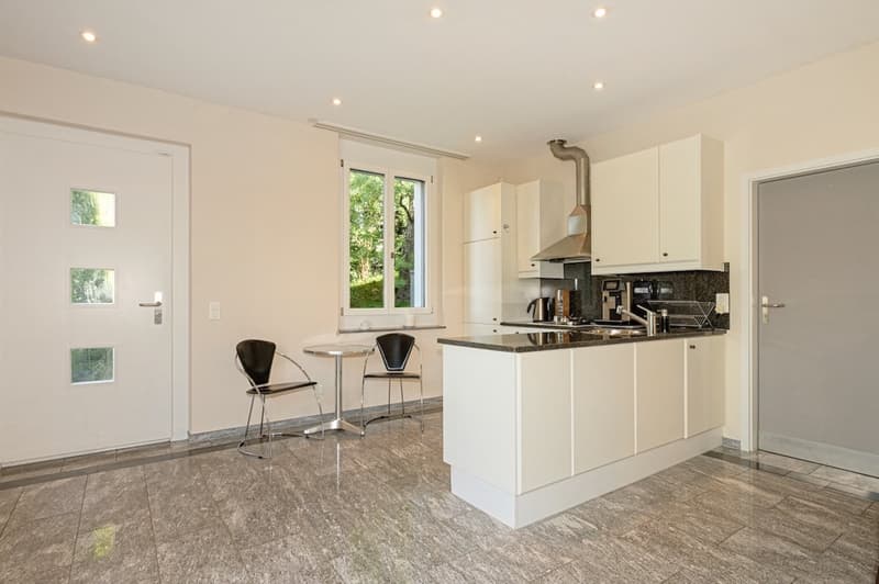 modern kitchen with white cabinets, granite countertops, stainless steel appliances, small table with chairs, white doors