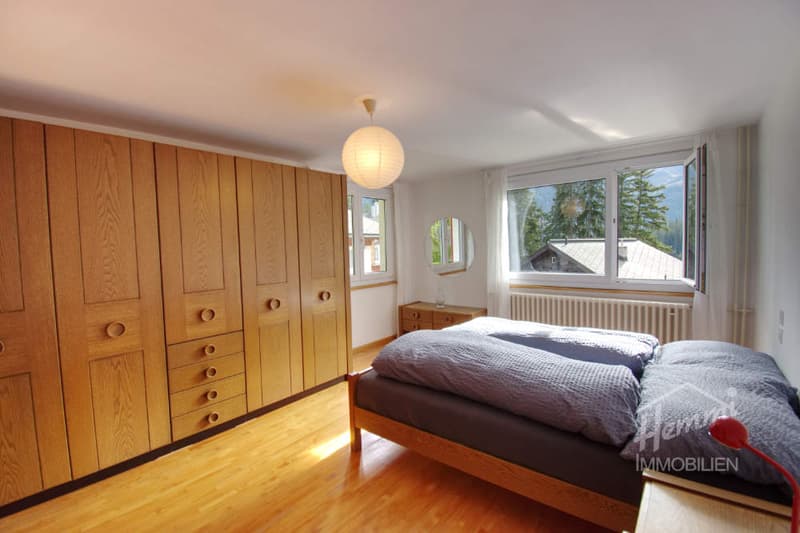 bedroom with wooden floor, large wooden wardrobe, double bed, lamp, window, view