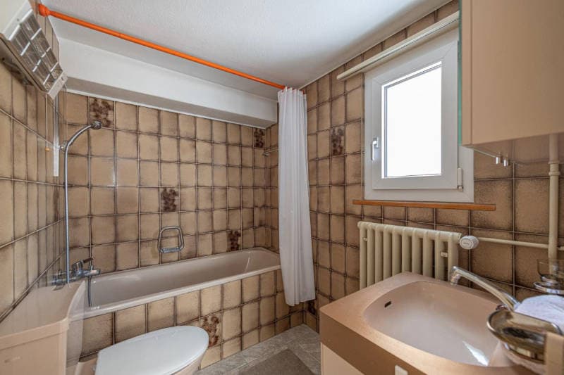 Bathroom with bathtub, toilet, sink, and radiator
