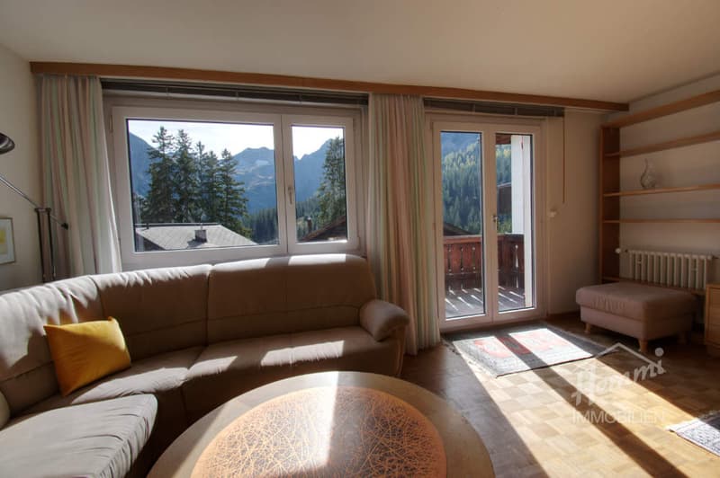 L-shaped sofa, coffee table, large windows, balcony, wooden floor, radiator, shelves, rug