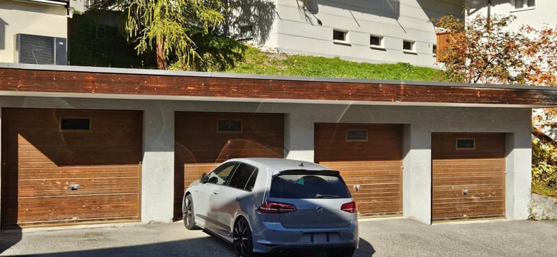 Garage with three parking spaces, wooden doors, car parked in front