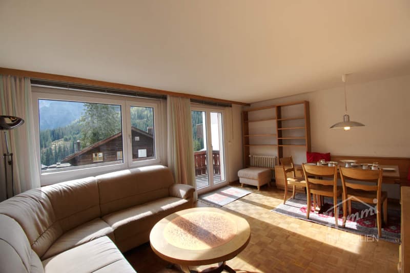 living room with sofa, coffee table, dining table, chairs, large windows, balcony, wooden floor