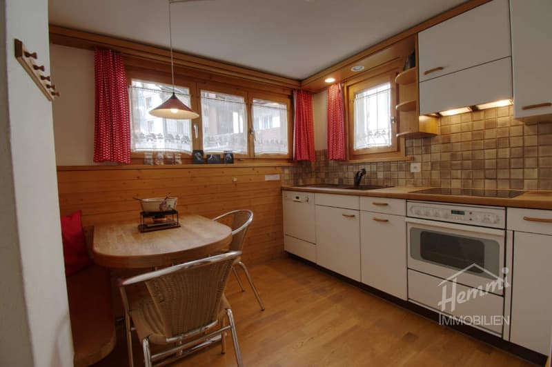 kitchen with wooden floor, white cabinets, white appliances, dining table, chairs, windows with red curtains