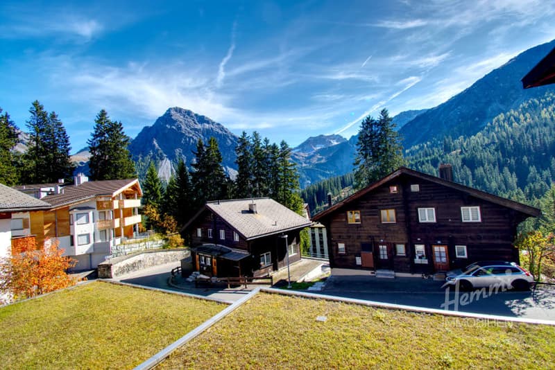 3 houses, mountains in the background, car parked in front of the house
