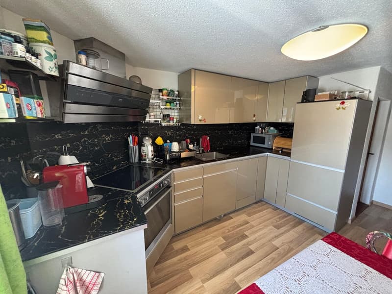 modern kitchen, wooden floor, black marble countertops, white cabinets, integrated appliances, overhead light