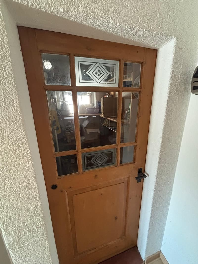 wooden door with glass panels, white walls, reflective glass, objects visible through door
