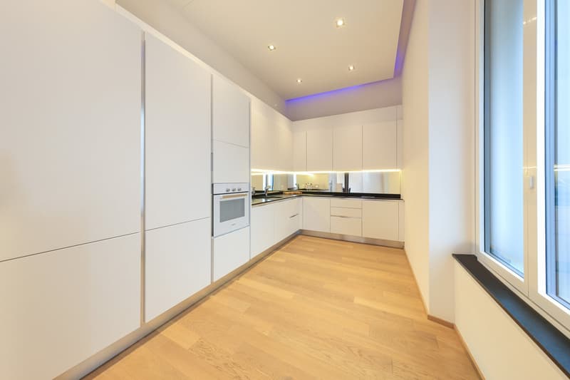modern design, white cabinetry, built-in appliances, wooden flooring, large window